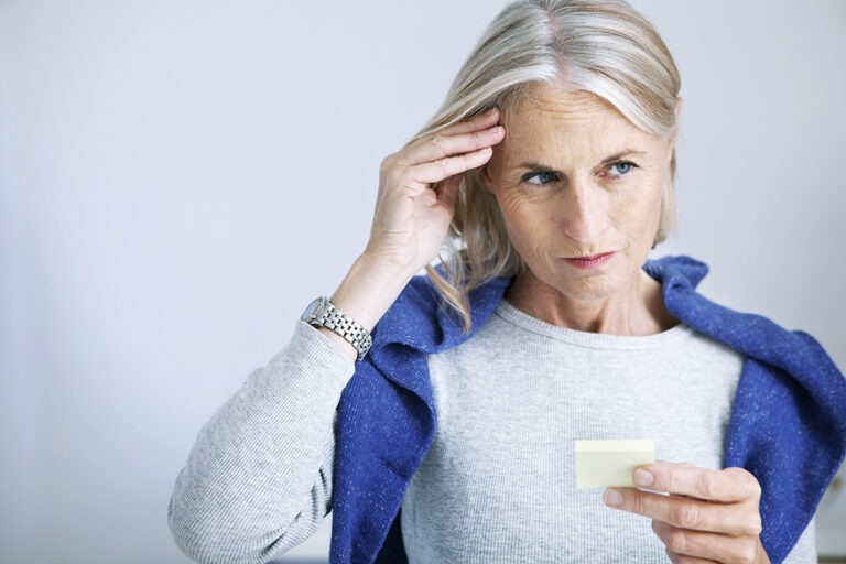 Woman holding her head with a post card in her hand