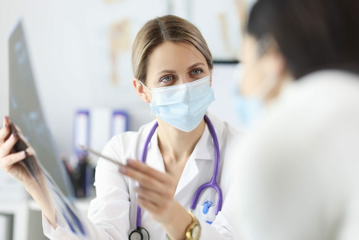 Doctor in protective mask showing patient X ray
